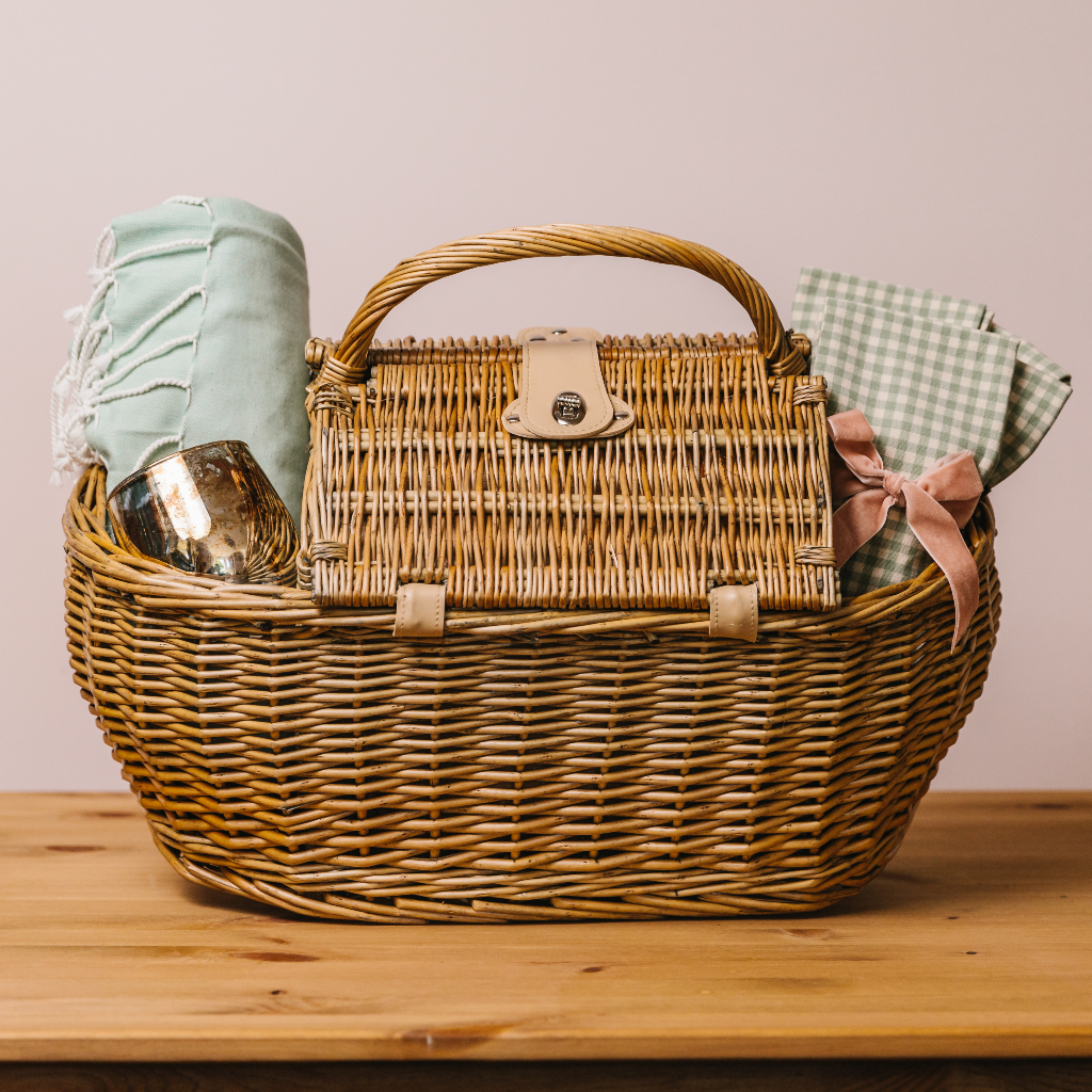 The closed Summer Willow Picnic Hamper showing a hamman throw, gingham napkins (with pink velvet napkin bow) and burnished bronze candle holder