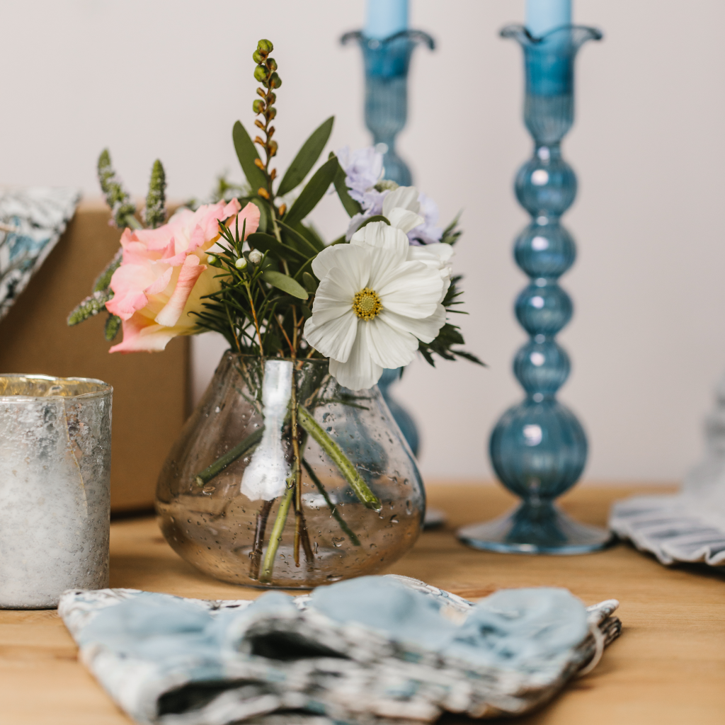 Speckled Valois bud vase with wildflowers in front of powder blue hand blown glass candlesticks.