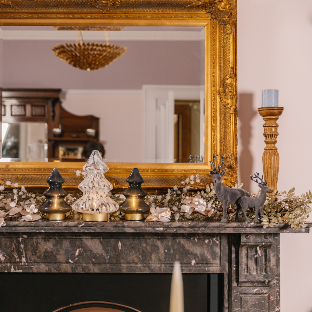 Blue, silver and gold festive mantlescape featuring glass LED festive tree lamps, pewter and silver reindeer and pale blue pillar candles
