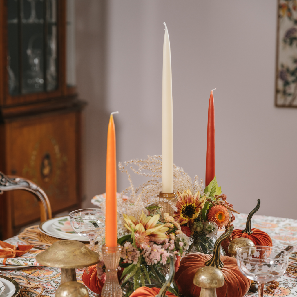 Pumpkin, ivory and rust autumn tapered candle set next to autumn flowers