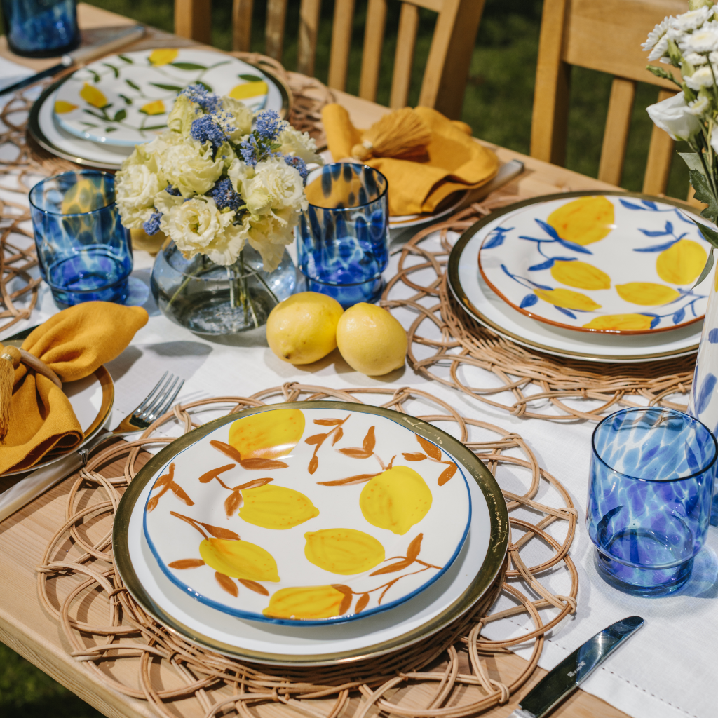 The Lemon Grove Collection with blue tortoise glass tumblers, lemon design plates and woven rattan placemats