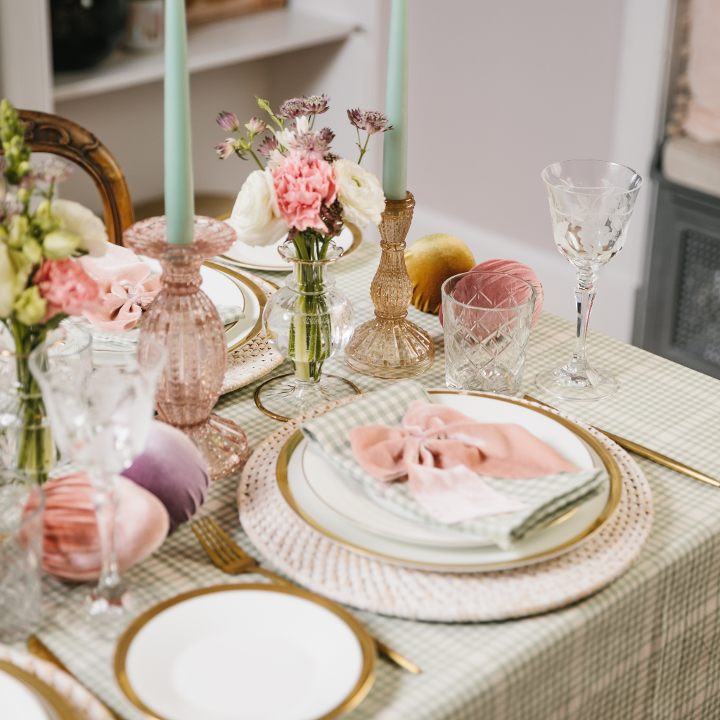 Duck egg and cream gingham tablescape with pink and champagne gold glass candlesticks, white rattan charger plates and pastel velvet Easter egg decorations