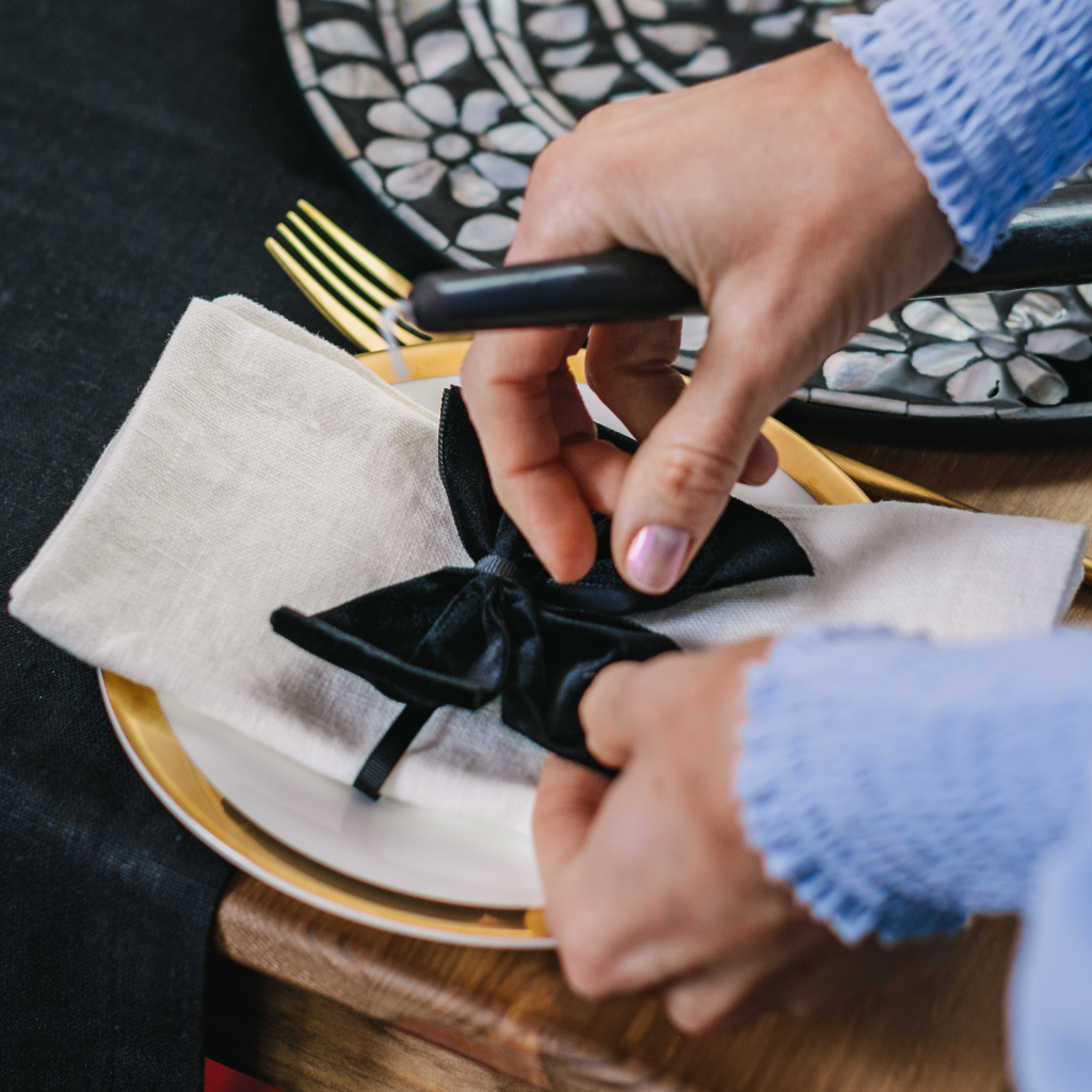 Setting the Magical Monochrome tablescape with black velvet napkin bows and white linen napkins.