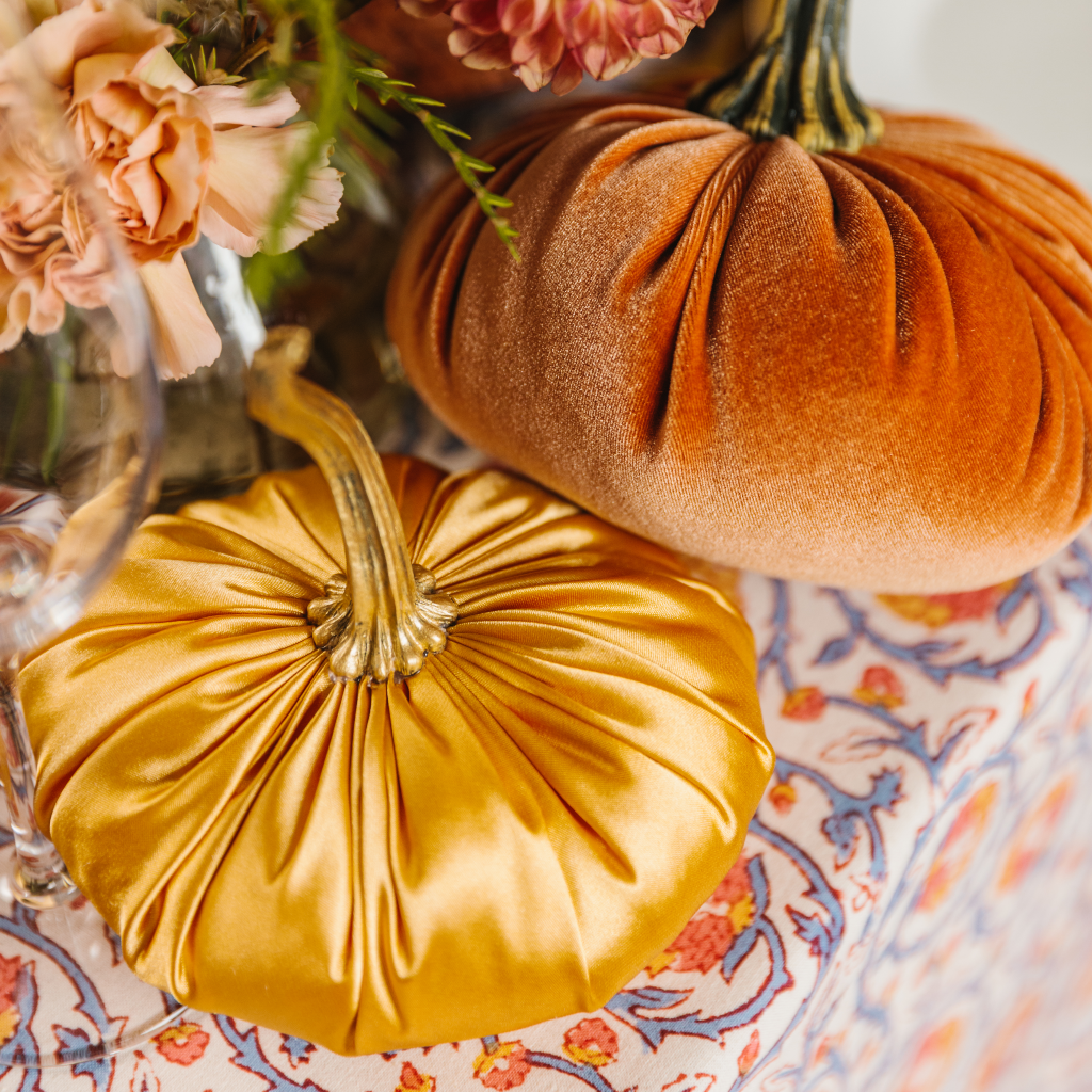 Luxury gold satin pumpkin with gold resin stalk placed alongside an orange velvet pumpkin fall decoration