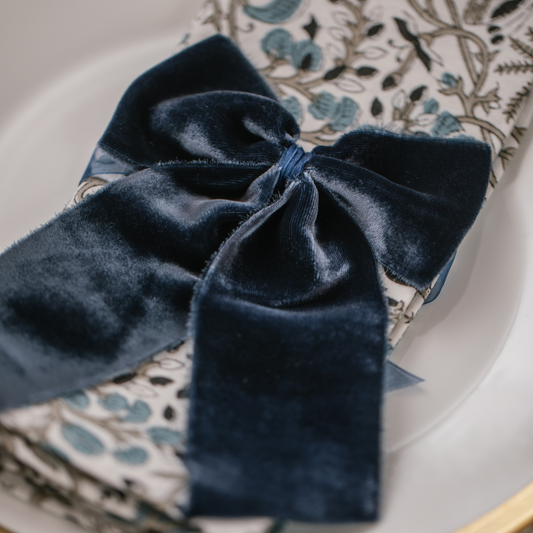 Luxury navy velvet napkin bow tied round a blue Indian block printed patterned napkin