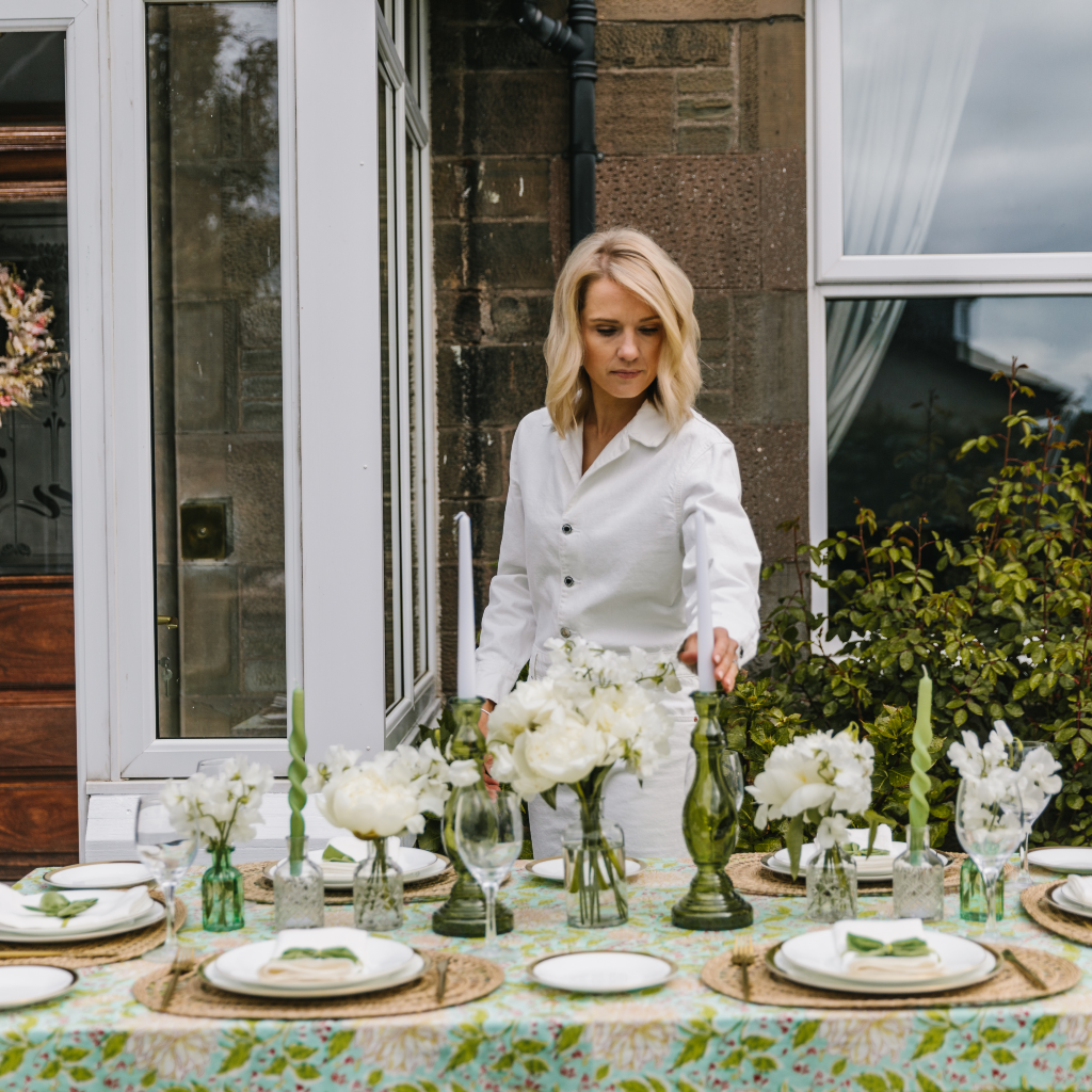Setting an al fresco mint and moss tablescape with statement green glass candlesticks on a vibrant indian block print tablecloth in shared of green and cream.