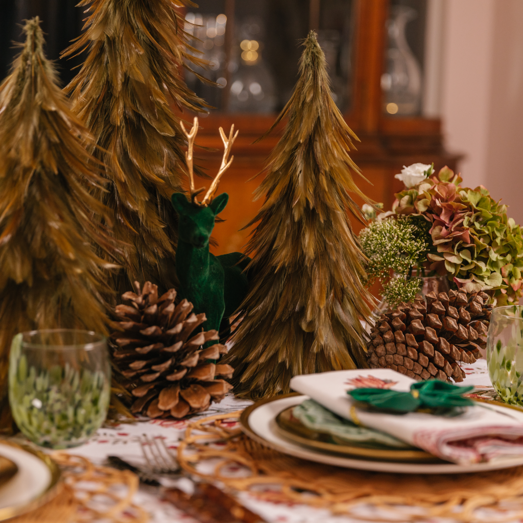 Green flocked stag next to feather Christmas trees, giant pine cones and murano glasses
