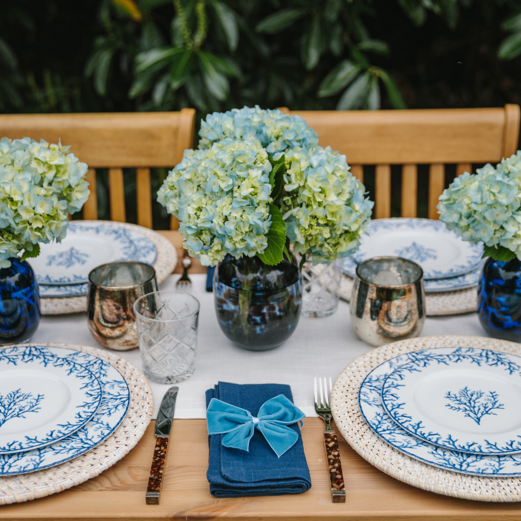 Large blue leopard dappled glass vase set on blue and white al fresco tablescape with hydrangea