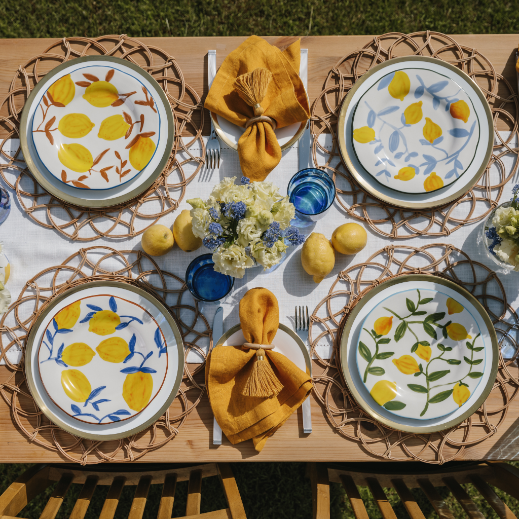Set of four lemon design summer plates with on tablescape with woven rattan placemats and a white cotton table runner