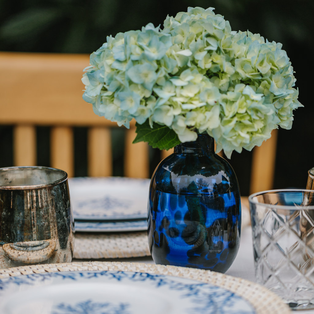 Close up of royal blue tortoiseshell vase displaying green and blue hydrangea
