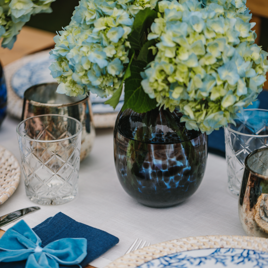 Dappled detail on blue tortoiseshell glass vase displaying blue and green hydrangea