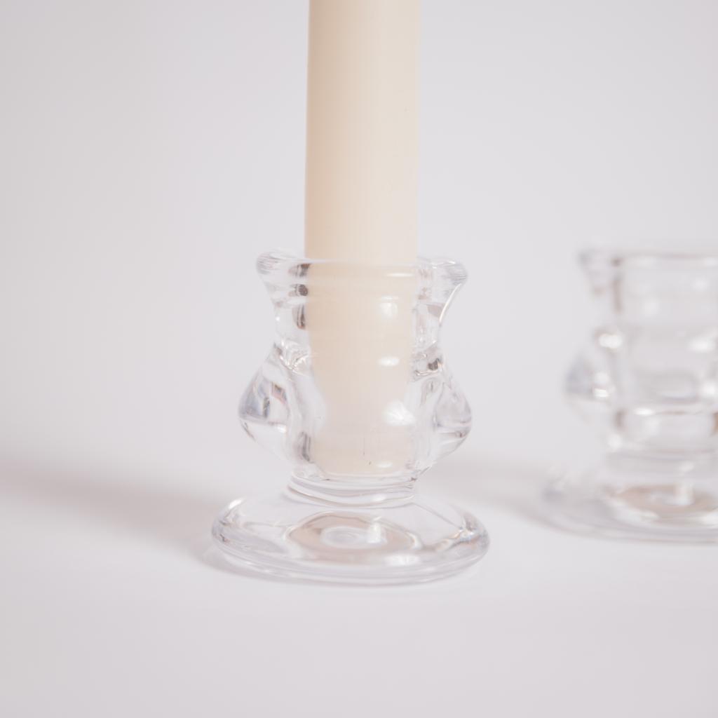 Close up of clear glass tulip candle holder holding an off white tapered dinner candle