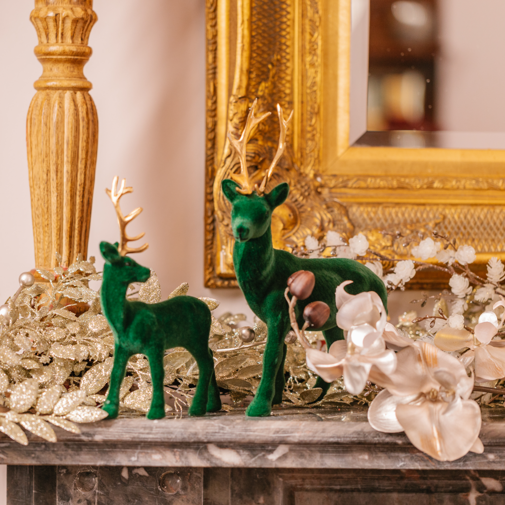 Large forest green flocked reindeer decoration next to small green reindeer with gold antlers