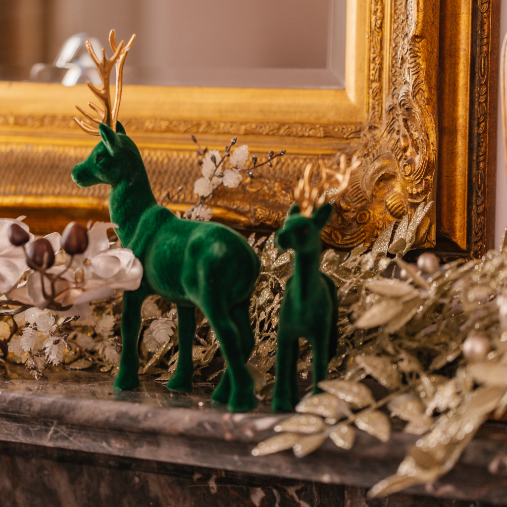 Large and small green flocked stags on marble mantle with gold Christmas garland