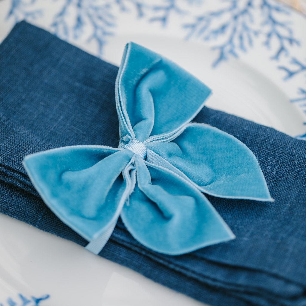 Kingfisher blue velvet napkin bow on navy blue linen napkin