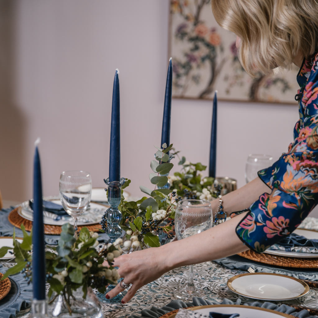 Kate Fairlie, director of Truffle Tablescapes, laying the Twilight Tablescape with navy blue tapered candles in hand blown, powder blue dinner candle holders