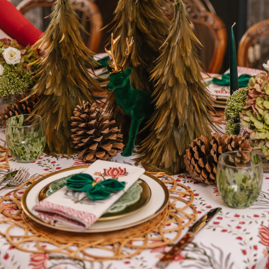 Green velvet and gold reindeer on Christmas tablescape with feather trees and giant pinecones