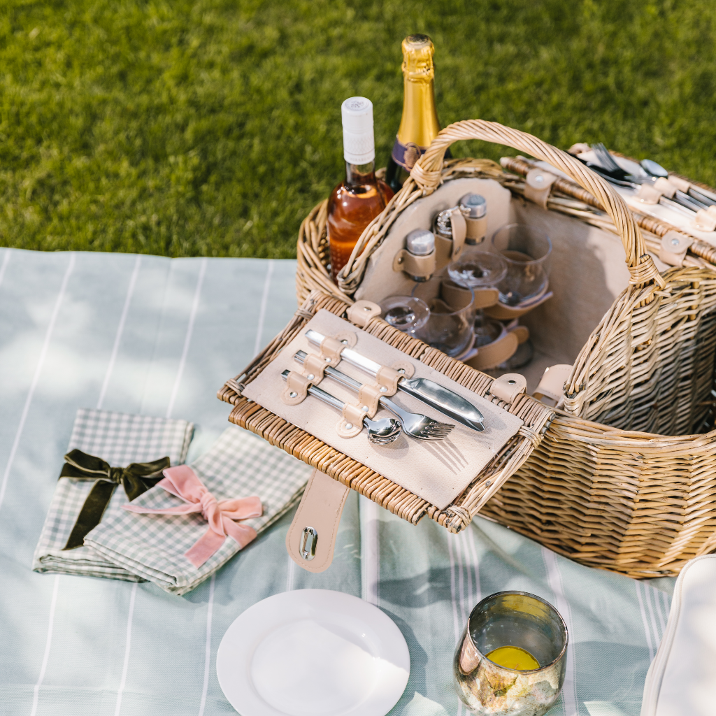 Alfresco picnicking with a luxury futted hamper, cotton throw and napkins alongside glassware, crockery and silver cutlery