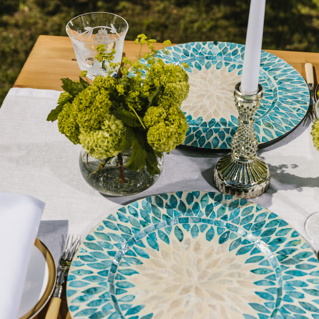 Side on view of aqua and white table setting showing white linen table runner as tablescape foundation