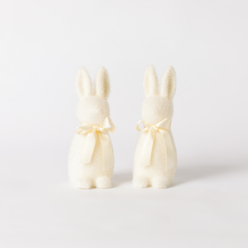 A pair of cream flocked bunny decorations with matching ribbon ties round the neck.