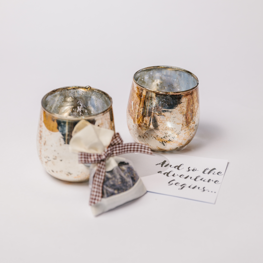 Two burnished bronze candle holders, a wedding gift card and a pouch of dried lavender with gingham tie