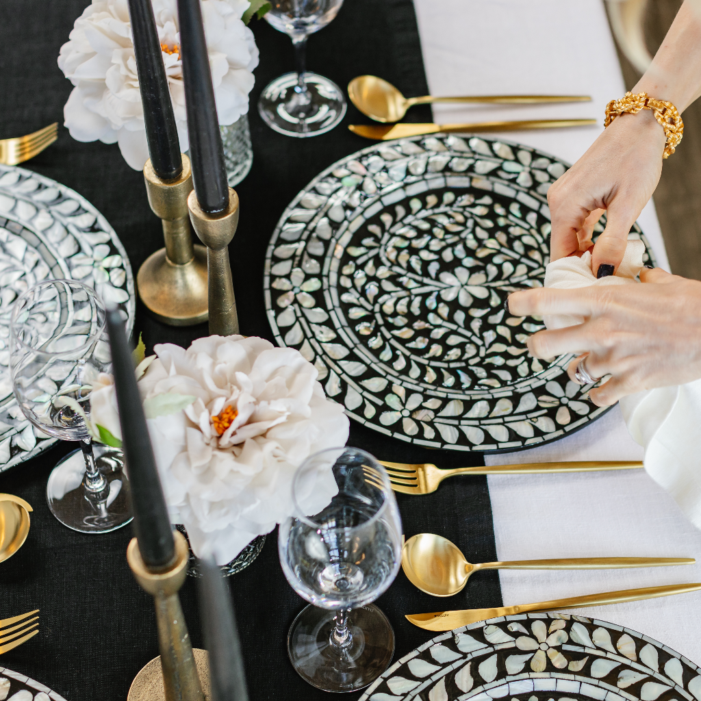 Laying Truffle Tablescapes' Magical Monochrome tablescape in a box with a classic 100% black linen table runner, black and white mother of pearl charger plates, antique brass candlesticks and black tapered dinner candles