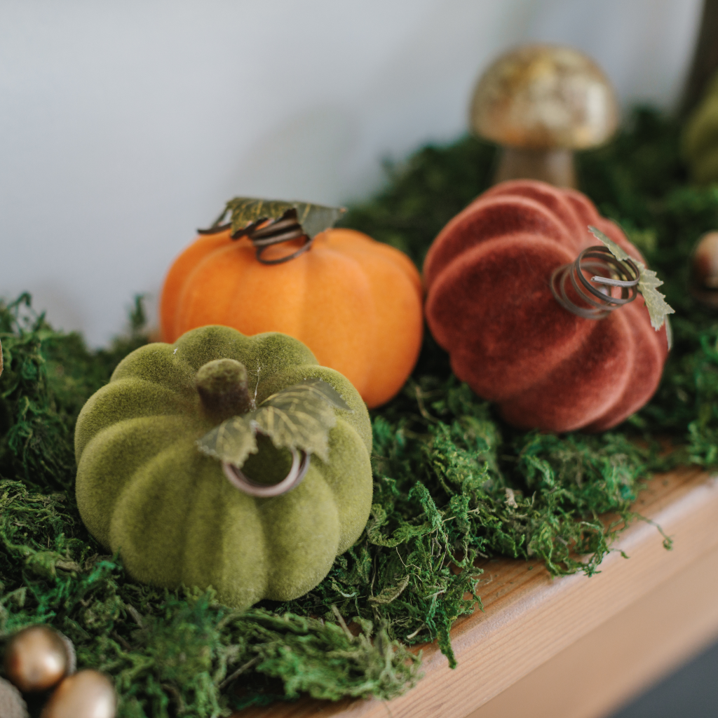 Rust, pumpkin spice and moss green flocked pumpkin decorations on autumn moss mantlescape