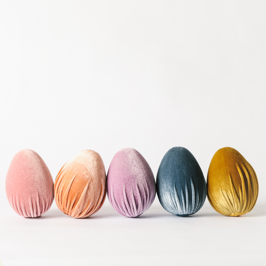 Row of large handmade velvet Easter egg decorations in pink, peach, lilac, slate blue and soft gold