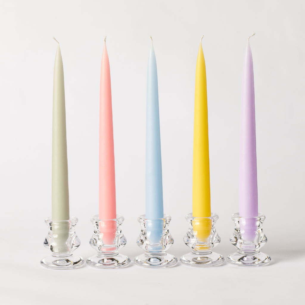 A set of pastel coloured tapered dinner candles in clear glass tulip candle holders including candles in pale apple green, sweetie pink, sky blue, buttercup and lavender.