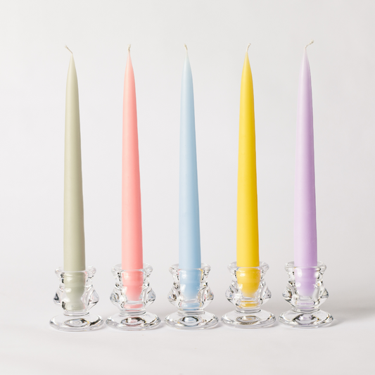 A set of pastel coloured tapered dinner candles in clear glass tulip candle holders including candles in pale apple green, sweetie pink, sky blue, buttercup and lavender.