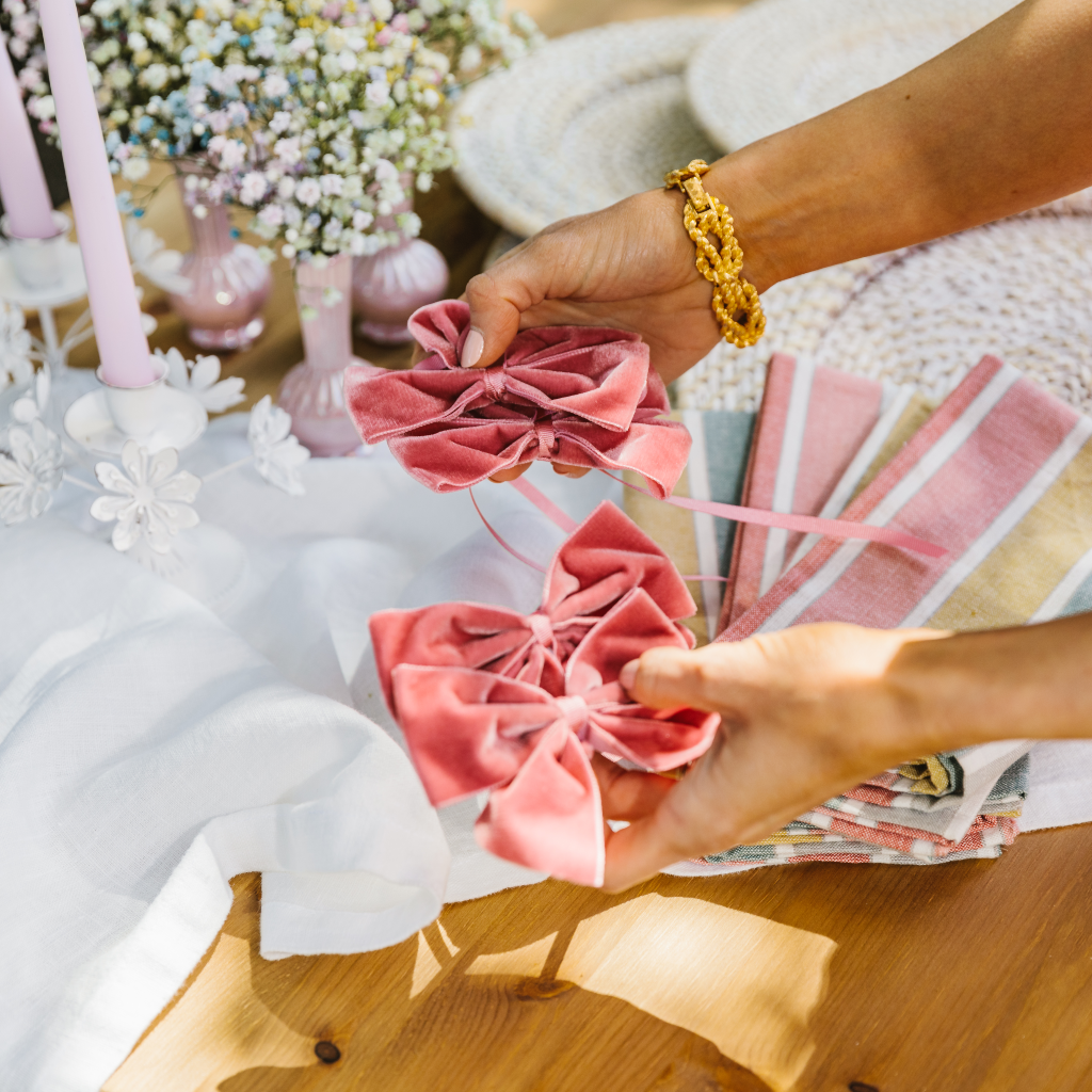 Hands holding pink velvet napkin bows ready to place next to sorbet summer al fresco tableware collection
