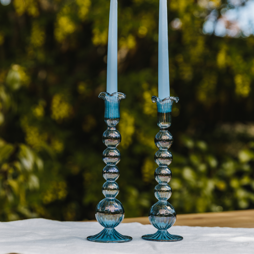 Two hand blown powder blue glass candle holders with pastel blue tapered candles.