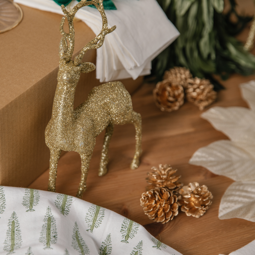 Gold glitter stag standing next to gold pine cone decorations