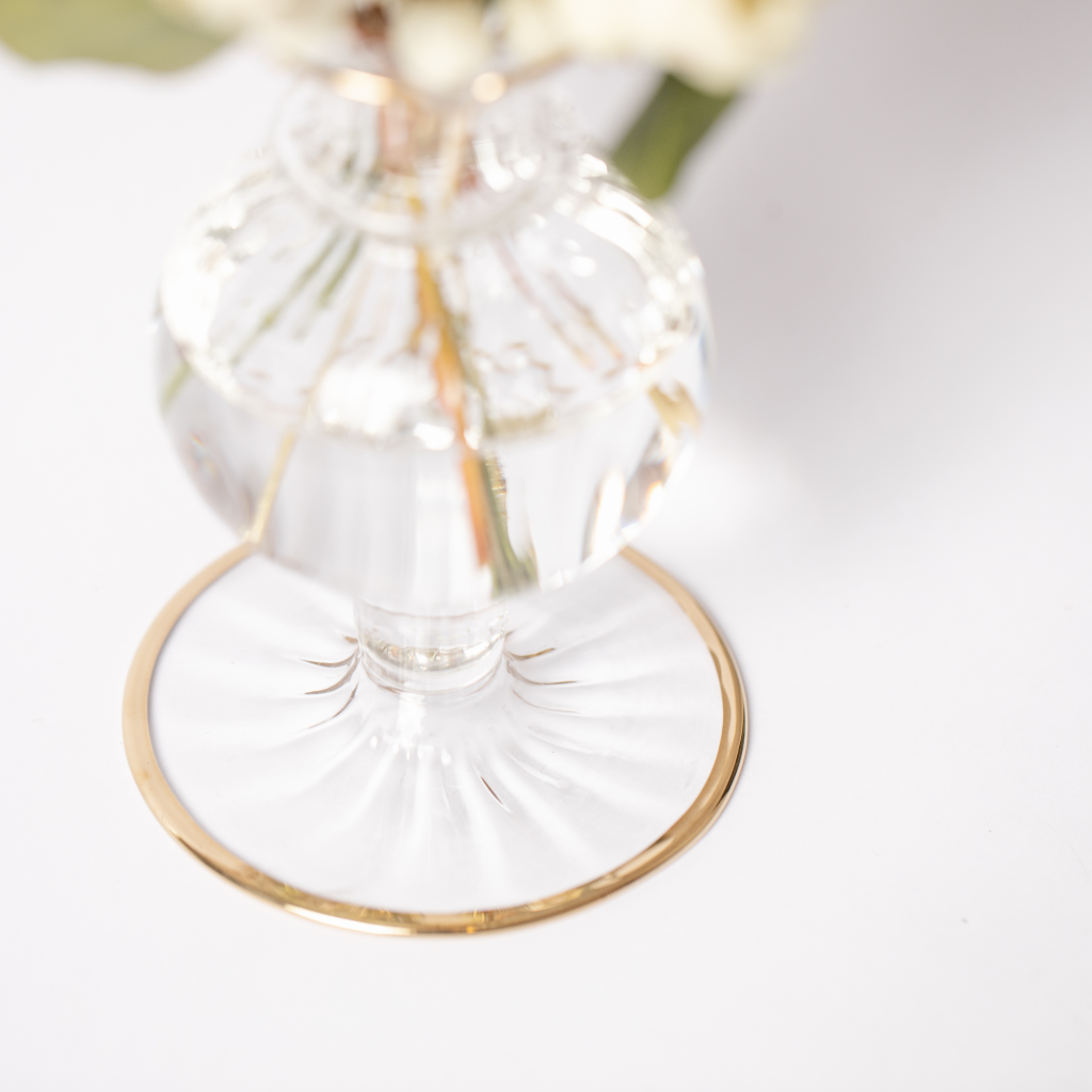 Round flat base of delicate clear bud vase with gold trim.