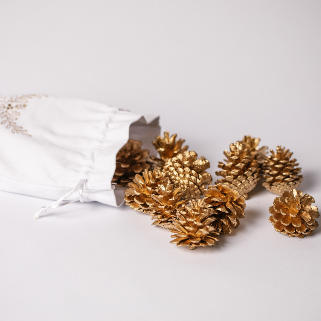 White cotton pouch containing golden pine cone decorations