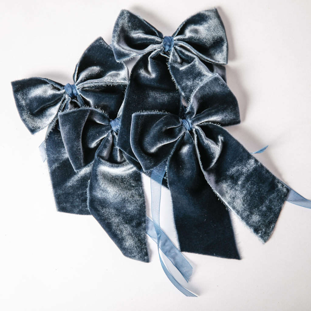 Four luxury navy blue velvet napkin bows with navy ribbon set on white background,