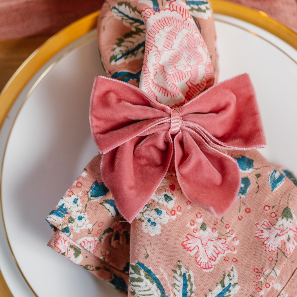 Top down view of peony pink ruffled napkin tied with a large pink velvet napkin bow.