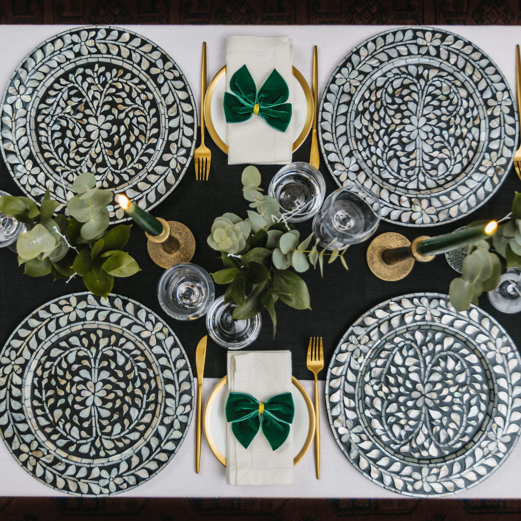 Top down flat lay image of black and white tablescape including statement monochrome mother of pearl charger plates, gold candlesticks, black dinner candles and flower displays