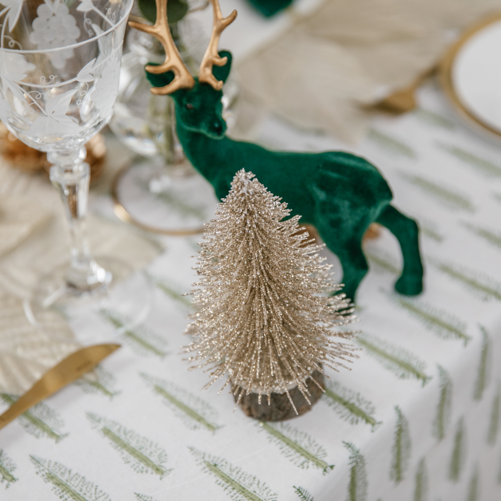 Flocked forest green stag with gold antlers next to sparkly gold brush tree decoration