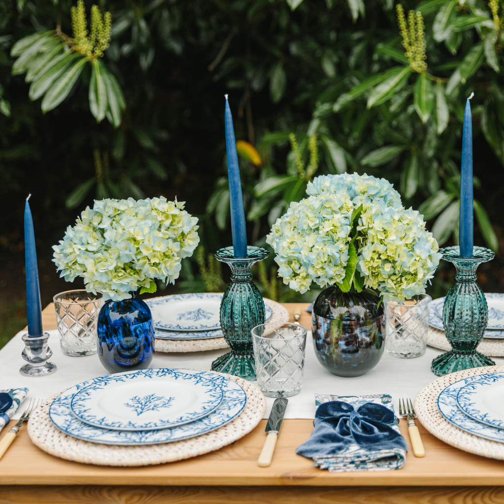 Truffle's Santorini al fresco tablescape with blue coral design plates, blue glass candle holders, blue leopard dappled vases and navy tapered candles