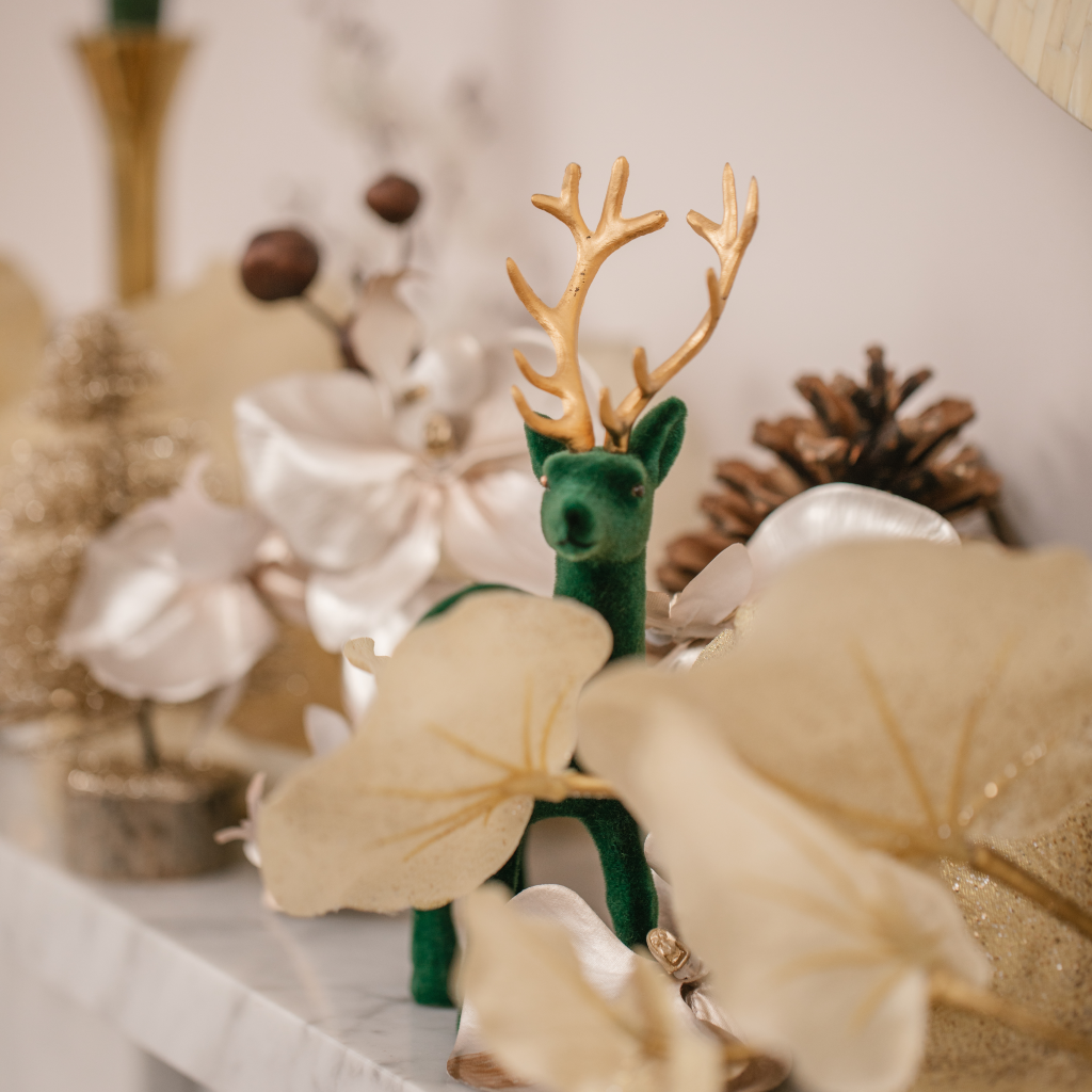 Forest green stag decoration peeking from behind gold foliage on Christmas mantlescape