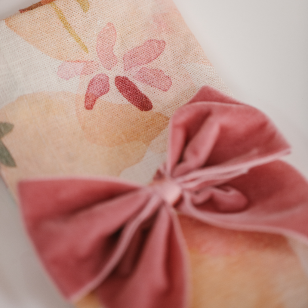 Close up of Truffle's Peaches and Cream linen dinner napkins with dappled pink watercolour pattern and luxury pink velvet napkin bow tie