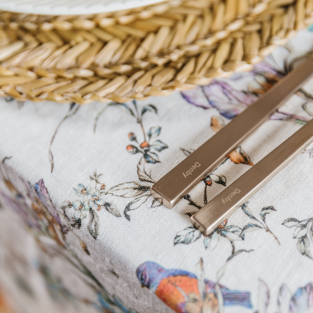 Close up image of wildflower pattern on 100% linen table runner. Seagrass placemat and Denby champagne gold crockery also feature.