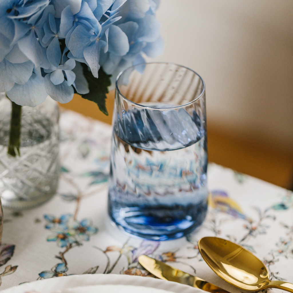 Blue swirled arc water glass on top of Wildflower Garden linen table runner.